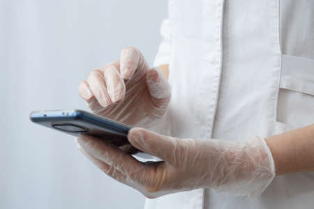 The doctors hands are close-up. A female doctor on a cell phone is texting or looking for something. Scrolls through the social media pageの写真素材