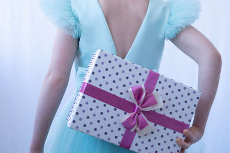 A teenage girl in an evening gown. The child holds the gift behind his back. Depersonalization