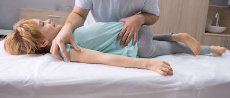 An osteopathic doctor is working with the child. Work on twisting the spine. Teenage girl patient...