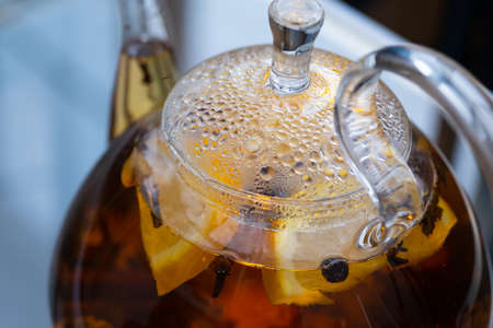 Transparent kettle with brewed tea inside. A fogged kettle lid. Droplets of water accumulated on the...