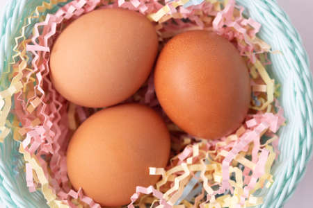 Large brown chicken eggs in a smart basket. Multi-colored tinsel. Easter conceptの写真素材