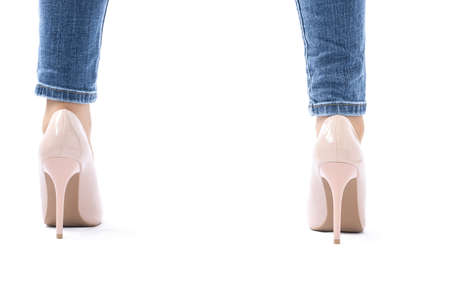 Slender female legs. Elegant patent beige high heels. Skinny jeans. The girl stands with her legs wide apart, rear view. There is space for textの写真素材