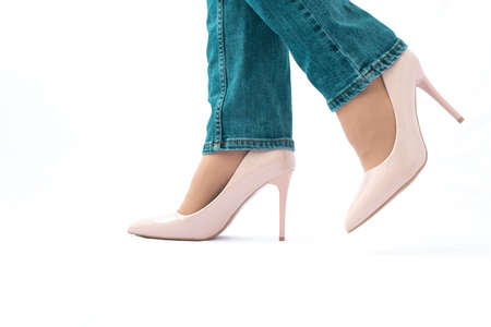 Slender female legs in high-heeled patent leather shoes. Green jeans. Fashion and Style. side view