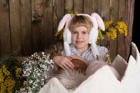 a teenage girl sits in a huge eggshell. Rabbits in the hands of a child. Easter attributes. happy...