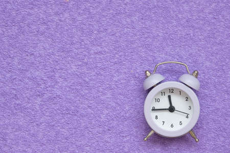 Alarm clock on a lilac suede background. There is space for text. Conceptの写真素材
