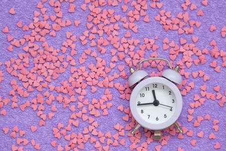 Concept of time for love. Beautiful postcard, top view. Among the hearts there is an alarm clock. There are also small hearts on the main background. Cards for Valentines Day close-upの写真素材