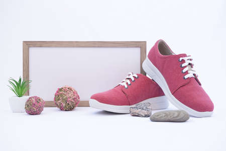 A pair of burgundy shoes in a shop window. There is a frame with space for text. The concept of environmentally friendly shoes. Shoes made from recycled materials. Nature design elements: grass, flowers and stones.の写真素材