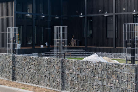 Fence decoration with natural stone. The house and the fence are black and gray