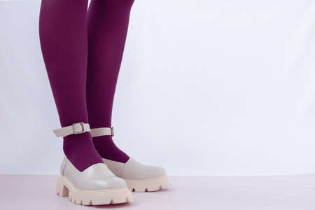 Womens legs in shoes with massive soles. Mary Jane shoes. Beige shoes and red tights. There is space...