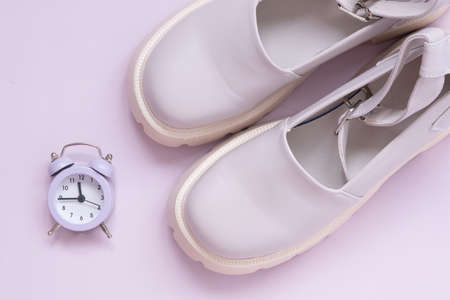A pair of shoes with strong soles. Alarm clock. The concept of fashion cycle. The concept of the...