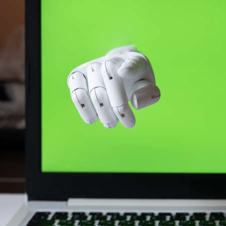 The robot hand points out of the laptop screen. Chroma key screen. The concept of interaction in social networks. The concept of interaction between artificial intelligence and humans. Communications in the space of the Internetの写真素材