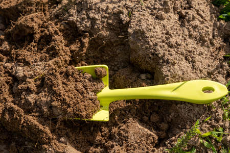 Shovel in the ground. A bed in the garden. Spring, summer time. Cultivation of the landの写真素材