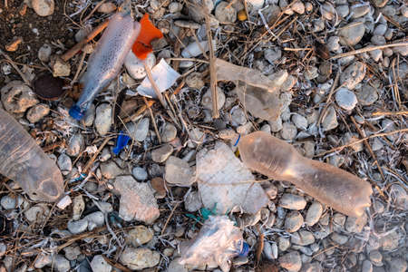 Plastic garbage on the seashore. Top view of a polluted beach. Stones and shells mixed with plastic. Environment conceptの写真素材