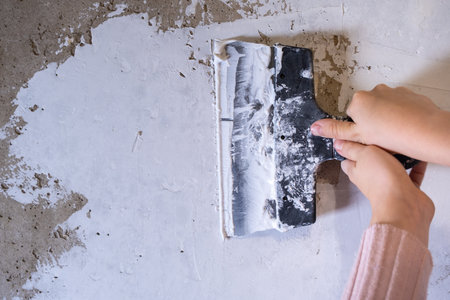 Childrens hands work with a spatula. Alignment of walls, finishing works. Applying puttyの写真素材