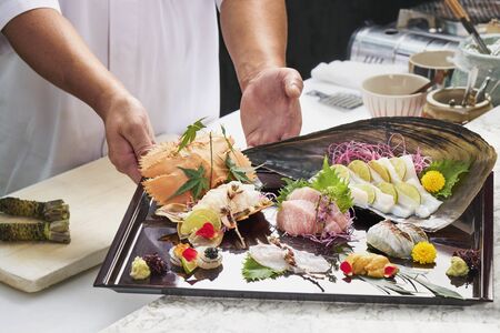 Premium Sashimi garnished with edible flowers in black plate on wooden background