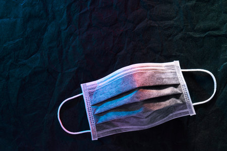 Medical mask or surgical earloop mask with red-blue light on Black paper background