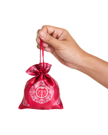 Red silk lucky gift pouch with traditional Chinese fortune symbol, held in a hand on white background. Festive decoration for Chinese New Year, celebrations and gifting. Isolated with clipping path.の写真素材