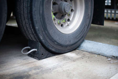 Semi Truck Trailer with Black Rubber Wheel Chock Securing the Trailer as an Additional Safety Step...