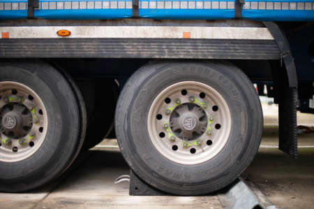 Semi Truck Trailer with Black Rubber Wheel Chock Securing the Trailer as an Additional Safety Step.のeditorial素材