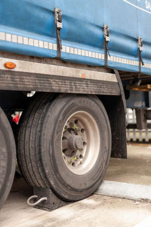 Semi Truck Trailer with Black Rubber Wheel Chock Securing the Trailer as an Additional Safety Step verticalのeditorial素材