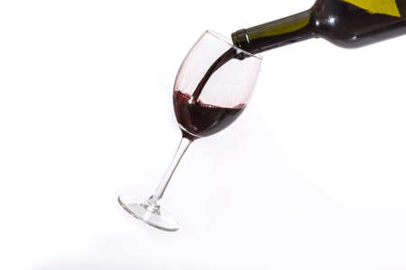 Red wine pouring in a wineglass on a white backgroundの写真素材