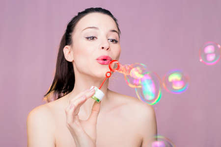 Beautiful woman blowing pink water balloons