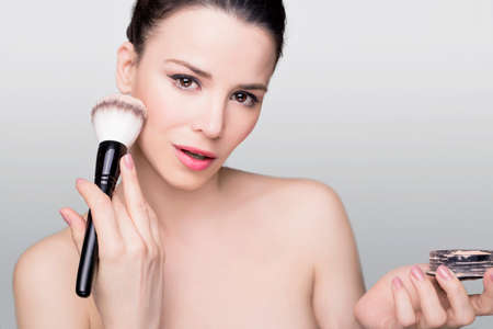 Beauty shot of a woman with makeup brushの写真素材