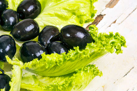 Black olives in a green salad leafの写真素材