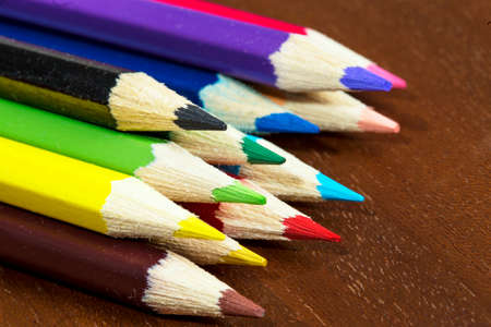 Multicolored crayons, pens on a wooden deskの写真素材