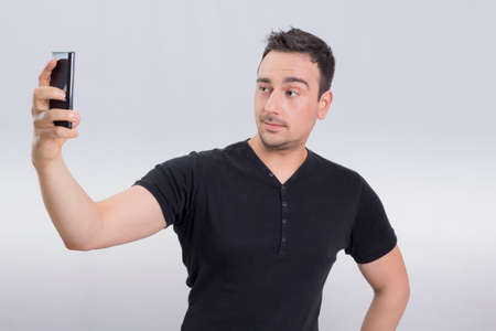 Man in black shirt taking a selfie on his cell phoneの写真素材