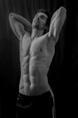 Handsome muscular man posing in dark shirtlessの写真素材