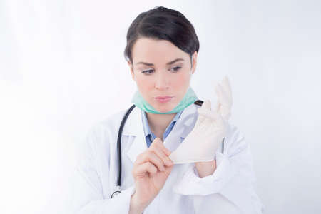 Female doctor adjusting rubber glovesの写真素材