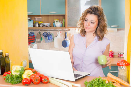 Happy housewife with a lap top in a kitchenの写真素材