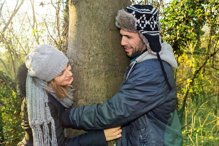Happy couple dating, hugging a treeの写真素材