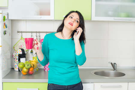 Housewife on a phone in the kitchenの写真素材