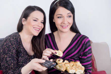 Two girl watching television and eating