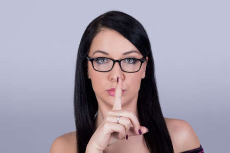 Girl with glasses making hush finger moveの写真素材
