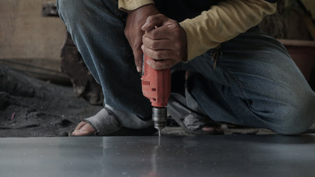 Worker using a drill to drill the tile on the floor.の写真素材