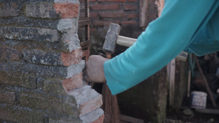 Close-up of a worker breaking a brick wall with a hammerの写真素材