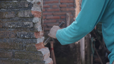 Worker using a hammer to break a brick wall, close upの写真素材