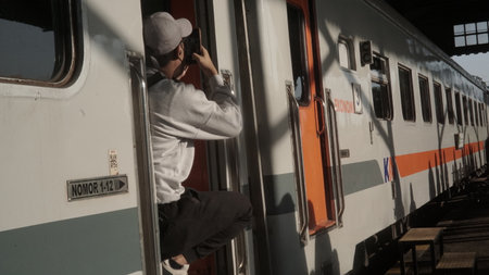 A young man taking a picture of a train at the station.