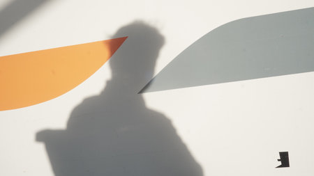 Shadow of a man on a white wall with an orange line.