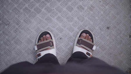 Selfie of feet in sandals on a steel floor background.