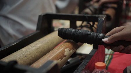 Hand of a Chinese craftsman in traditional clothes working on a wooden loom