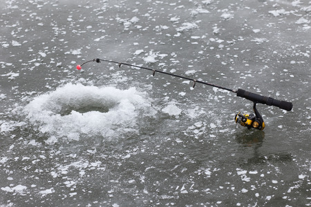A hole in ice and fishing rodの写真素材