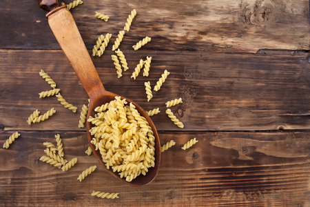 A pasta macaroni in a spoon on a wooden tableの写真素材