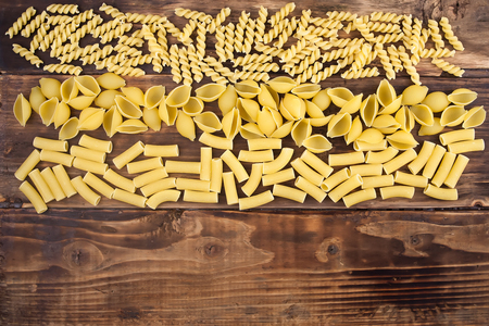 Different kinds of pasta macaroni on a wooden tableの写真素材