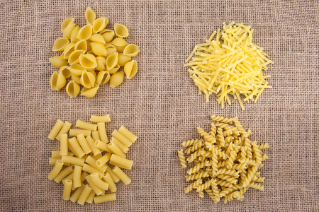 Different kinds of pasta macaroni on a textureの写真素材