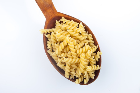 pasta macaroni in a wooden spoon on white background isolatedの写真素材