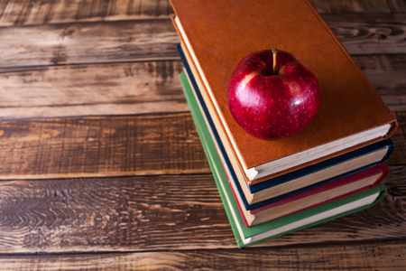 Books on the wooden table, red appleの写真素材